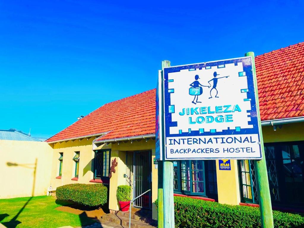 a sign in front of a house with a building at Jikeleza Lodge in Port Elizabeth
