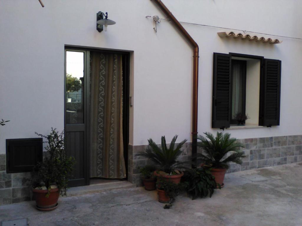 a house with a door and potted plants in front of it at L'Azzurro Apartment in Valderice
