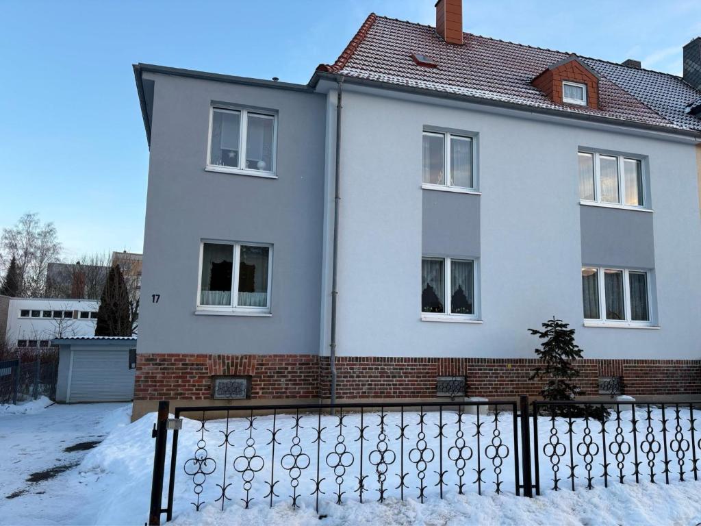 a white house with a fence in the snow at Gabis Ferienwohnung Zwickau in Zwickau