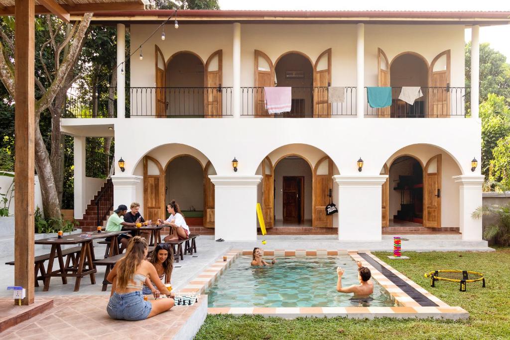 a group of people sitting in the pool in front of a house at Lucky U Hostel in Ahangama