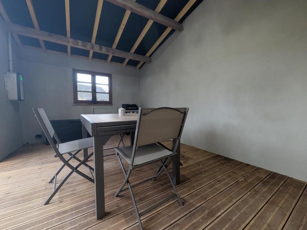 a table and two chairs in a room with a window at Gîte du joliment in Consigny