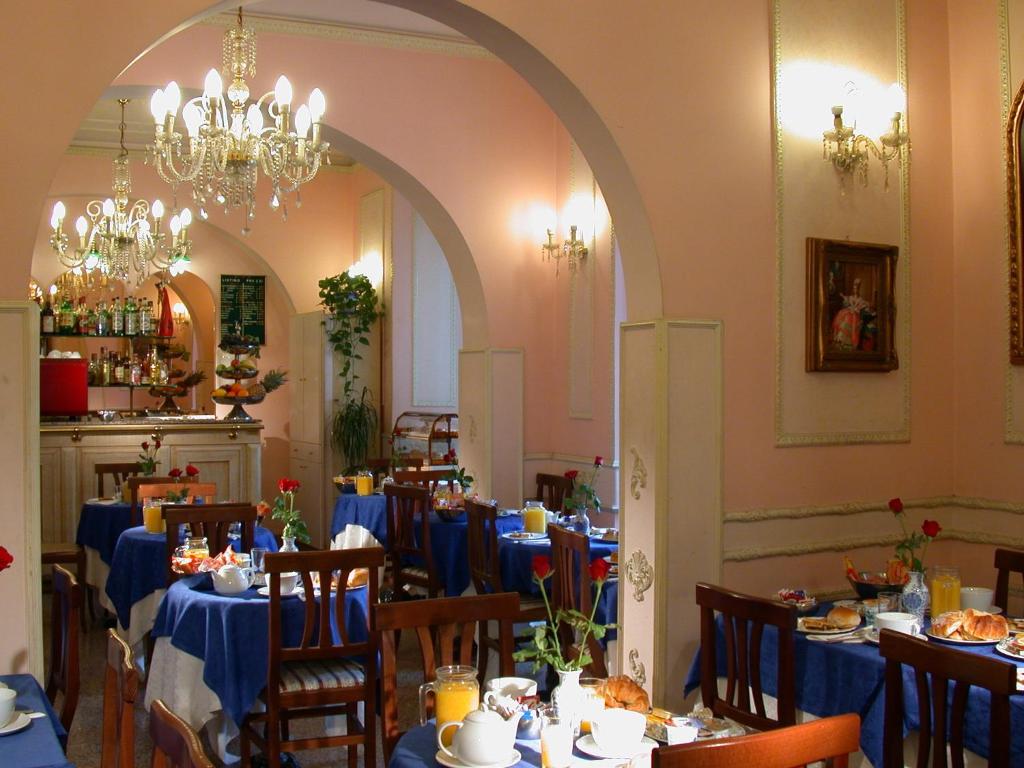 uma sala de jantar com mesas e cadeiras azuis e um lustre em Hotel Philia em Roma