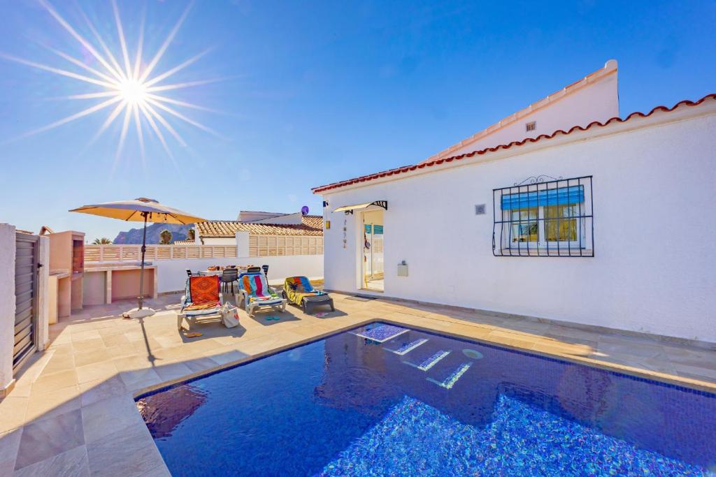 a swimming pool with two chairs and an umbrella at Villa Kuki - PlusHolidays in Ifach