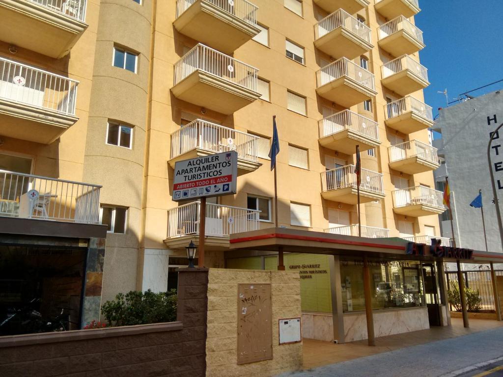 un gran edificio amarillo con un cartel delante en Apartamentos Turisticos Biarritz - Bloque I, en Gandía