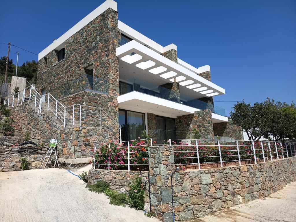 ein Steinhaus mit einer Steinmauer in der Unterkunft Plomari View Stone Apartments in Plomari