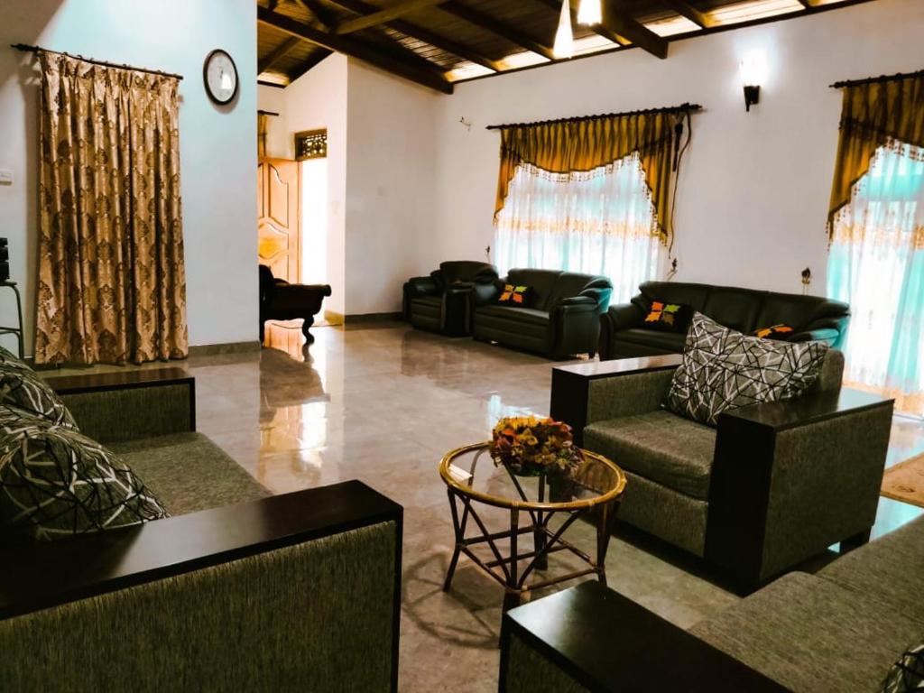 a living room with couches and chairs and a clock at Wellassa Hillside Villa in Kendagolla