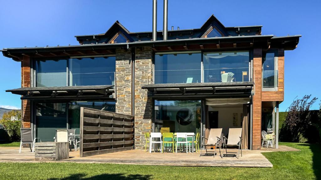 a house with glass doors and chairs on a patio at Morada la Tosa in Alp
