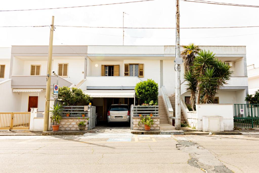 a white house with palm trees in front of it at Lily Flat - San Foca in San Foca
