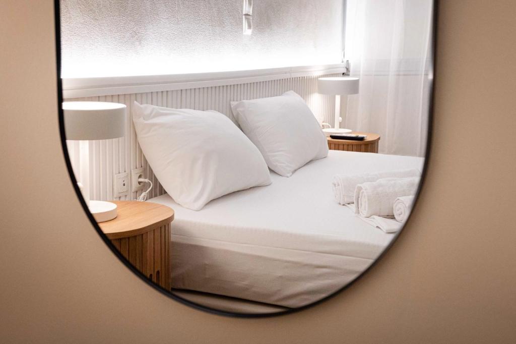 a bedroom with a bed with white pillows and a mirror at LUX Hotel 5 mins walk from port of Piraeus and metro station in Piraeus