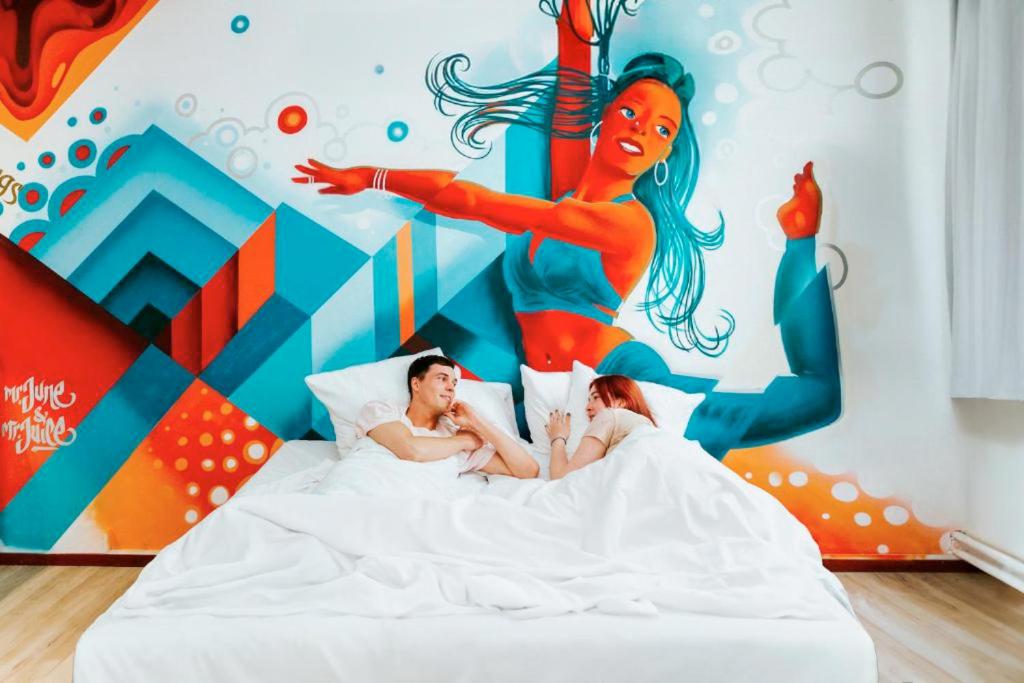 a man and woman laying in bed in front of a mermaid mural at Amsterdam Teleport Hotel - Free Parking in Amsterdam