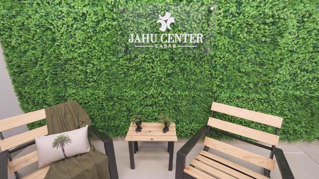 two benches sitting in front of a green wall at Jahu Center Casas Un 8 in Jaú