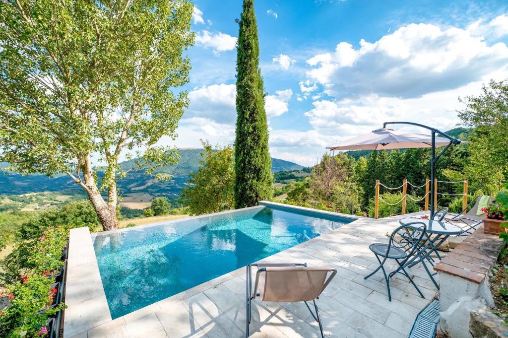 a pool with chairs and a table and an umbrella at Assisi Countryhouse in Assisi