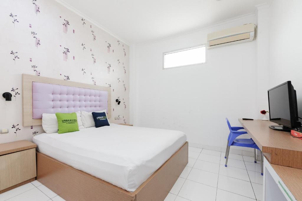a bedroom with a bed and a desk and a tv at Urbanview Hotel Niraz Banjarmasin by RedDoorz in Sungai Lutus