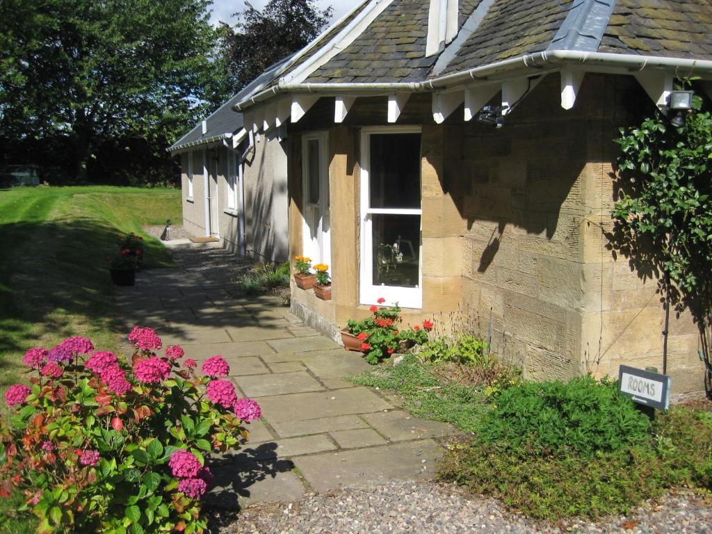 une petite maison avec des fleurs devant elle dans l'établissement Cantrip Cottage, à Cupar