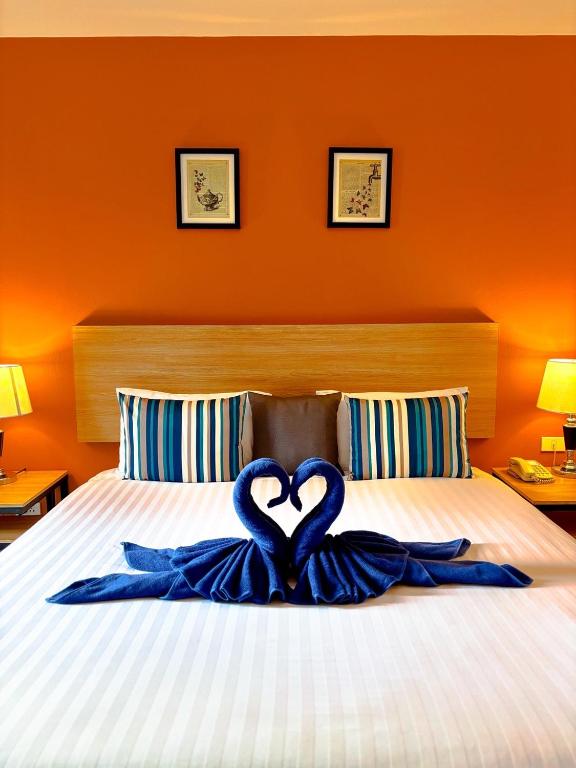 a bed with two blue ribbons forming a heart at Vogue Pattaya Hotel in Pattaya