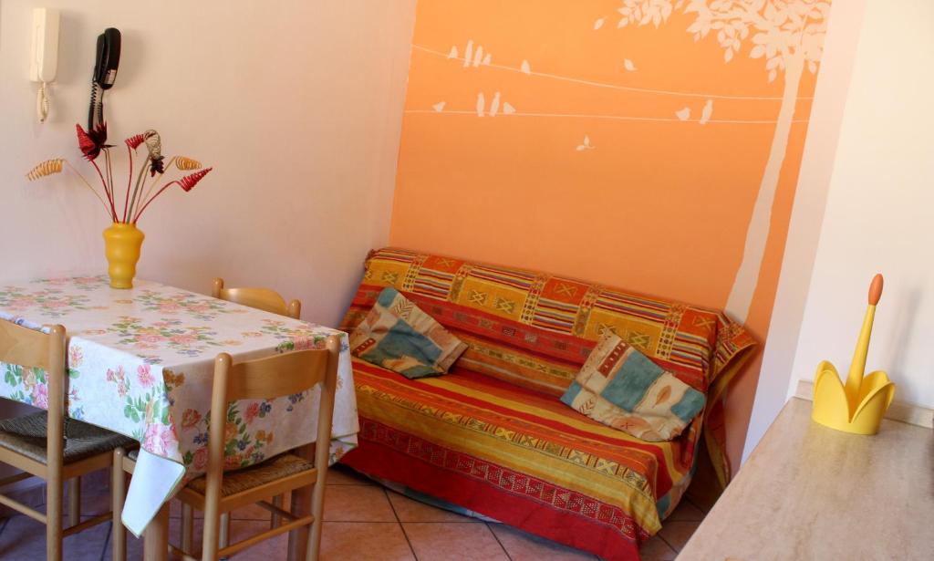 Una pequeña habitación con una mesa y una cama con colcha. en Appartamenti Tra gli Ulivi, en Bardino Nuovo