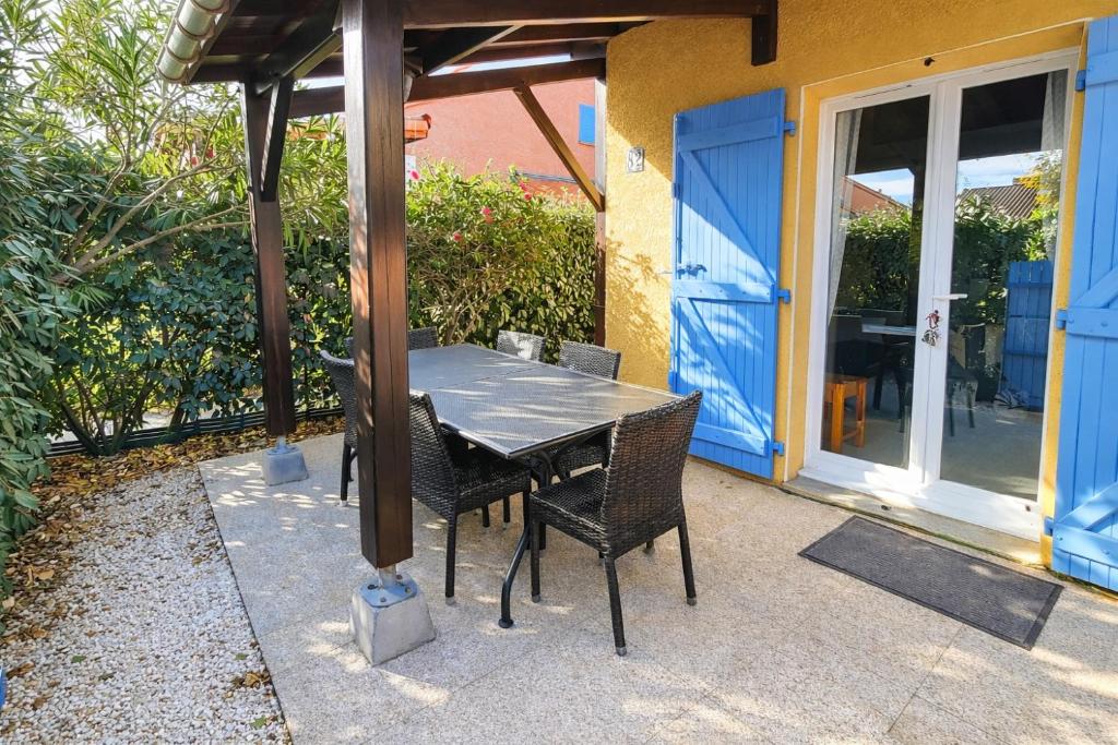 a table and chairs sitting under a wooden pergola at LES MARINES 2 - Villa en résidence avec piscine à 2 pas de la plage - Clim - parking in Saint-Cyprien