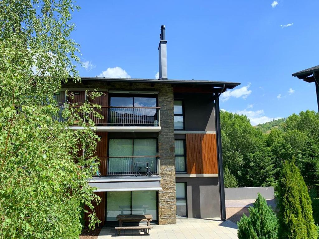 an apartment building with a balcony and trees at Apartament 5 persones Llar de Foc i Piscina in Saillagouse