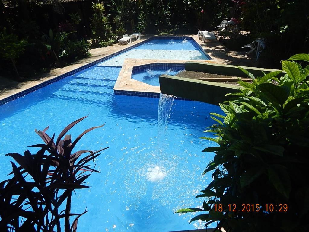 a swimming pool with a fountain in the middle at Vila dos Tupinambás in Boicucanga