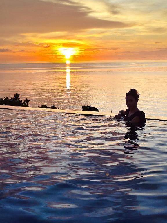 a person in a infinity pool with the sunset in the background at Viera Resort in Ngurblut