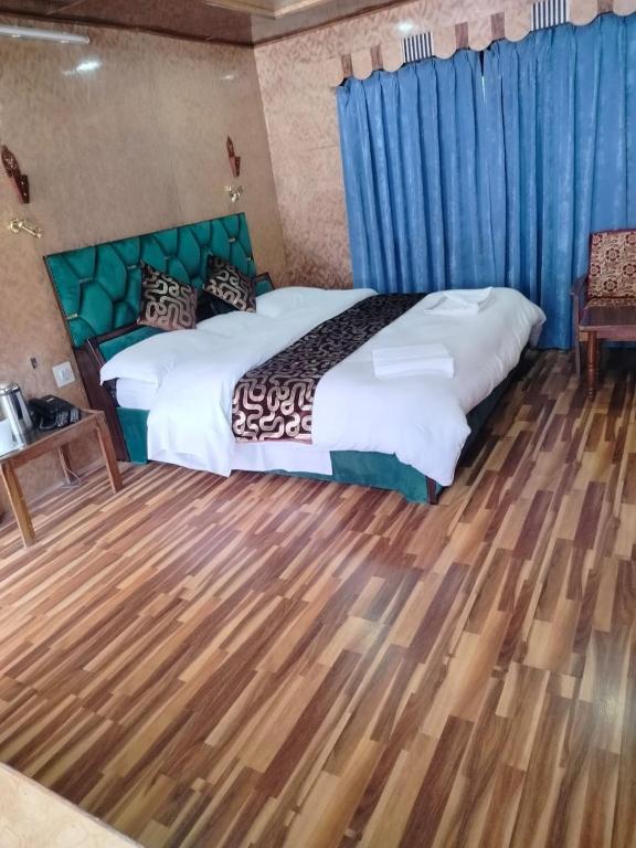 a bedroom with a large bed with a wooden floor at Siachen Hotel in Kargil