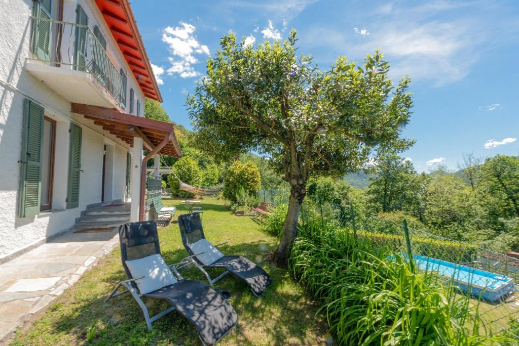 two chairs and a tree next to a house at Residenza sul Lago Maggiore in Luino