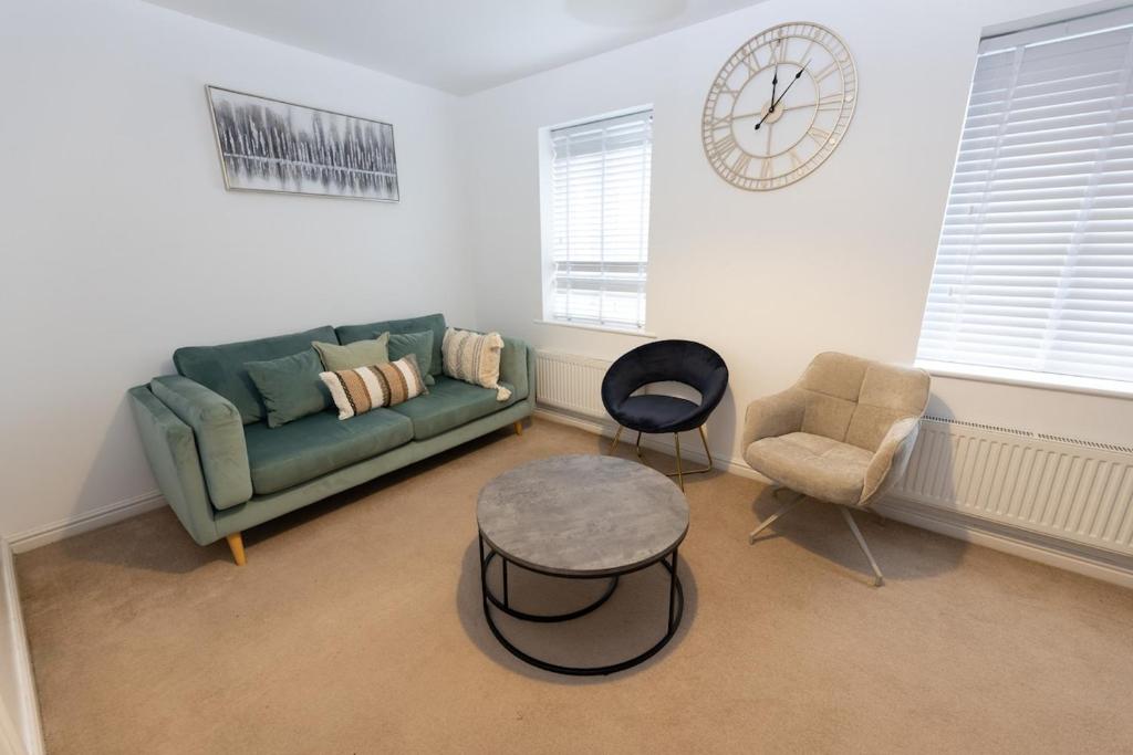 a living room with a couch and a table and a clock at Vantage Stays in Gloucestershire