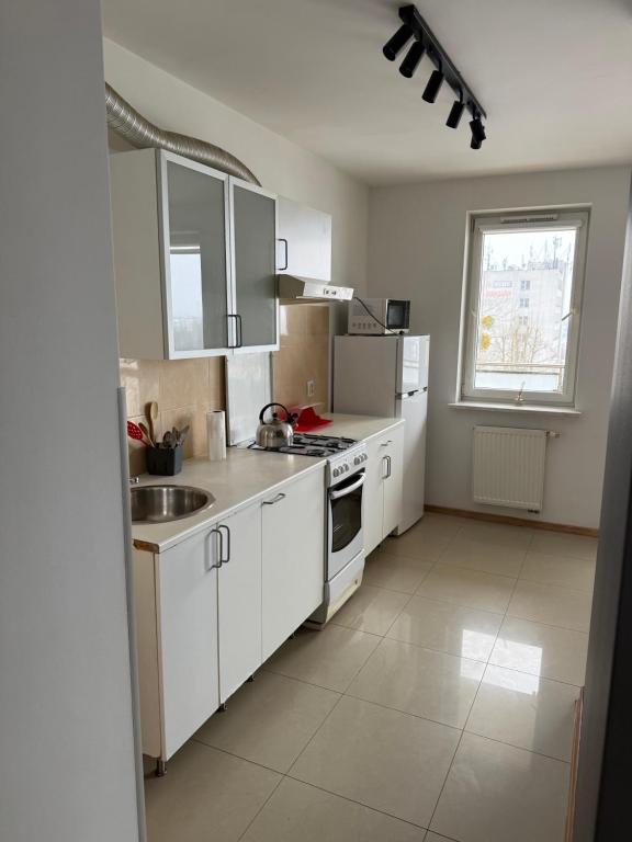 a kitchen with white cabinets and a sink and a window at UniqueView Apartament Jana Pawła in Białystok