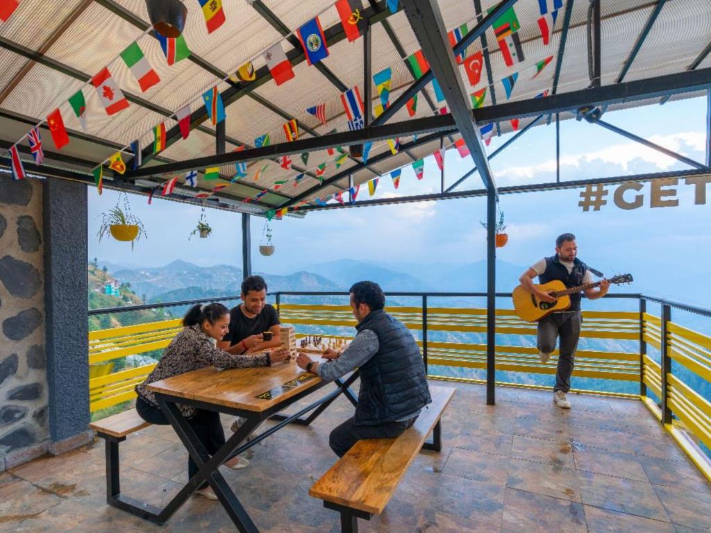 a group of people sitting at a table with a guitar at The Hosteller Kufri, Shimla in Kūfrī