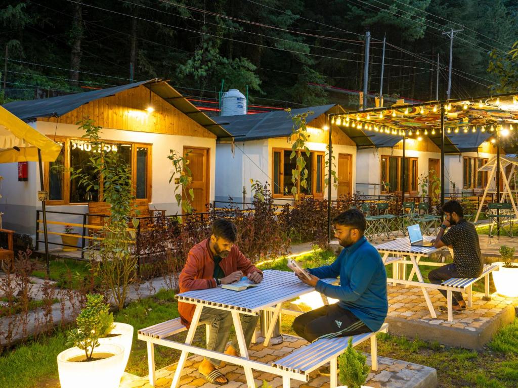 a group of people sitting at tables outside a house at The Hosteller Kasol, Riverside in Kasol