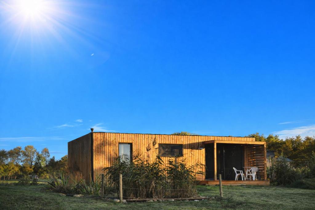 a small wooden house with the sun behind it at Studio bois Le Colibri à Chambley in Hagéville