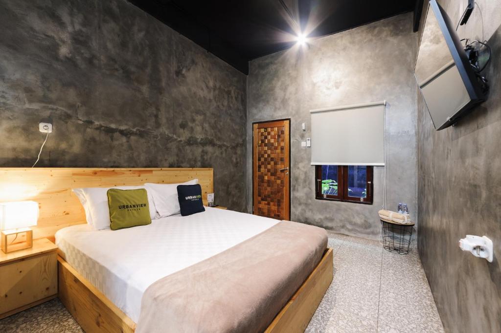 a bedroom with a large bed and a tv at Urbanview Hotel Syariah Keys Banjarmasin by RedDoorz in Terantang