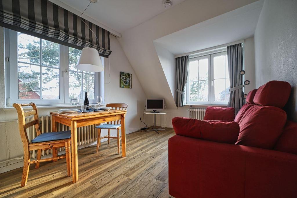a living room with a table and a red couch at Appartement-8 in Süddorf