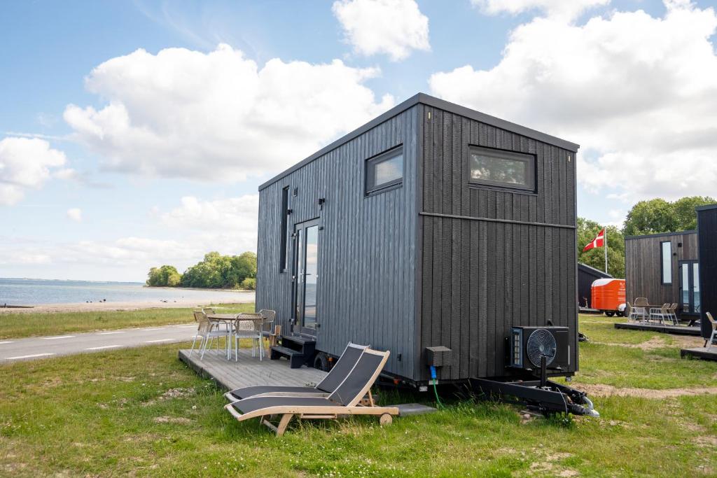 a black tiny house with a chair and a table at Tiny SeaSide - Loddenhøj in Aabenraa