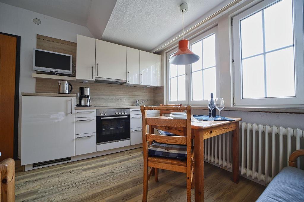 a kitchen with a wooden table and a table and a chair at Appartement-6 in Süddorf
