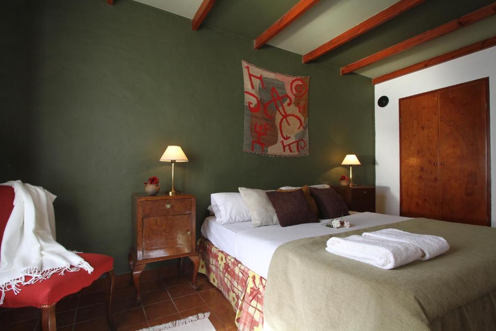1 dormitorio con 2 camas y silla roja en Hostería Lunahuana en Tafí del Valle