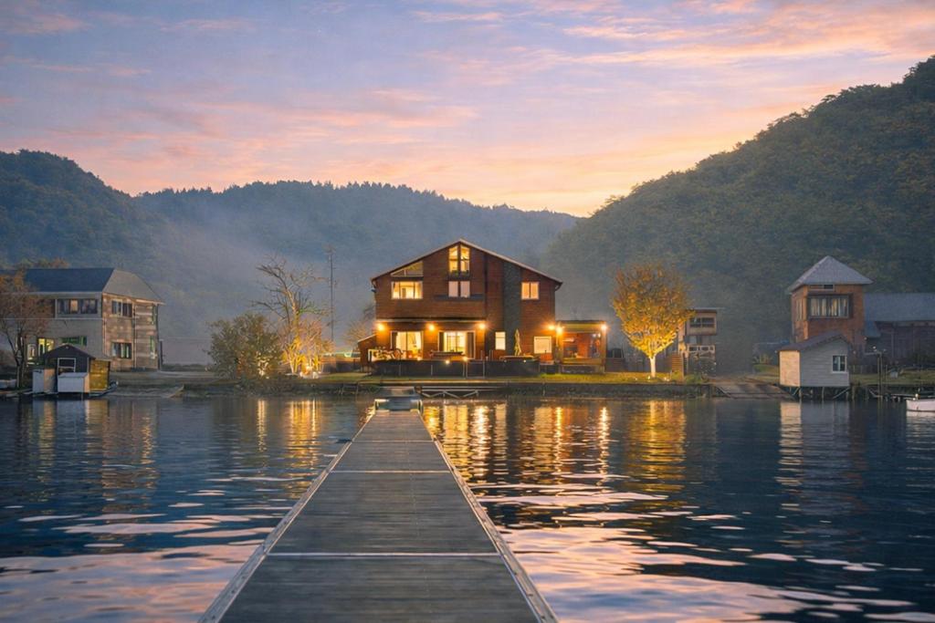 a house on a dock on a lake at sunset at The Lake House 野尻湖 in Shinano