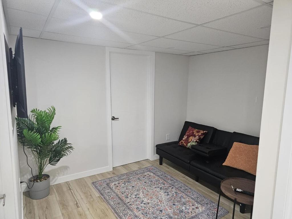 a living room with a black couch and a table at 2 Bedroom Suite in Transcona in Winnipeg