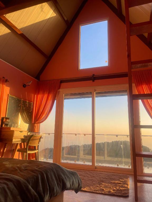 a bedroom with a bed and a large window at The Mystic Loft in Dharamshala