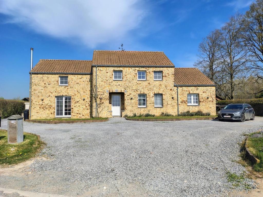 a brick house with a car parked in the driveway at La petite maison de Terre de Partage in Ohey
