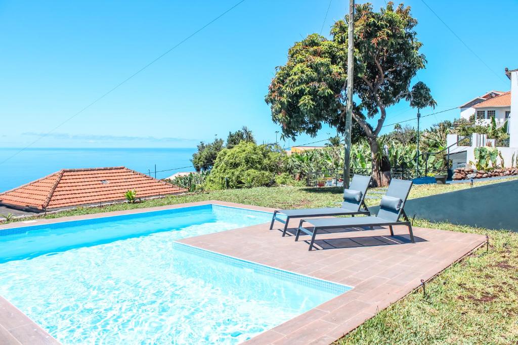 a couple of chairs sitting next to a swimming pool at Casa da Vila Apartments in Arco da Calheta