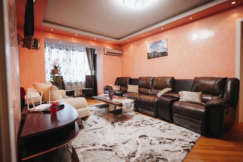 a living room with a leather couch and a table at Downtown Cozy Retreat - parcare inclusa in Vatra Dornei