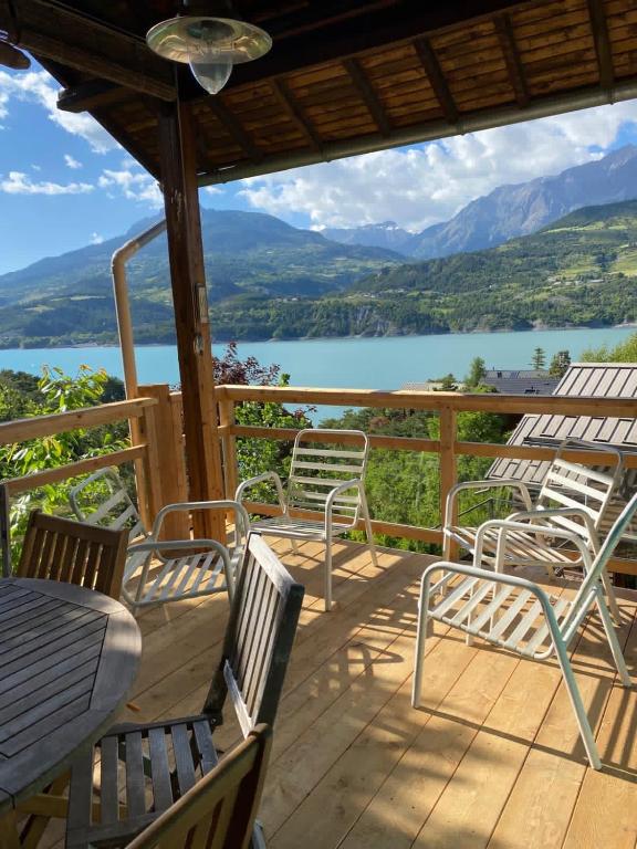 a deck with chairs and tables and a view of a lake at CHALET SAVINES LE LAC in Savines