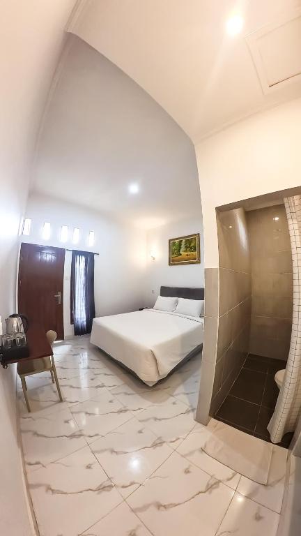 a bedroom with a white bed and a table and a chair at Arka Homestay Pesagi in Karangasem