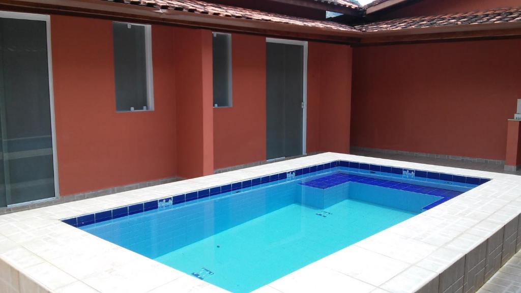 a large swimming pool in a room with red walls at Suite Recanto Cheiro Verde in Caraguatatuba