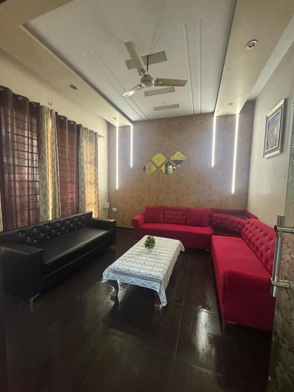 a living room with a red couch and a table at Auranest Stays Duplex Home in Ludhiana