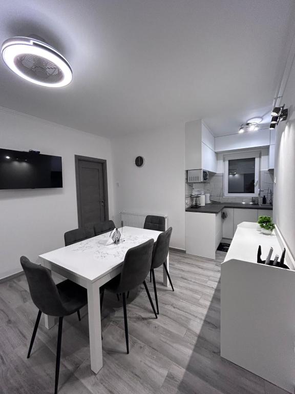 a white dining room with a white table and chairs at Alex Vip Apartman in Hajdúszoboszló