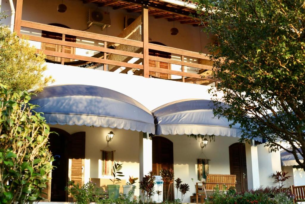 a white building with a balcony and an umbrella at Pousada Recanto da Ladeira in Paraty
