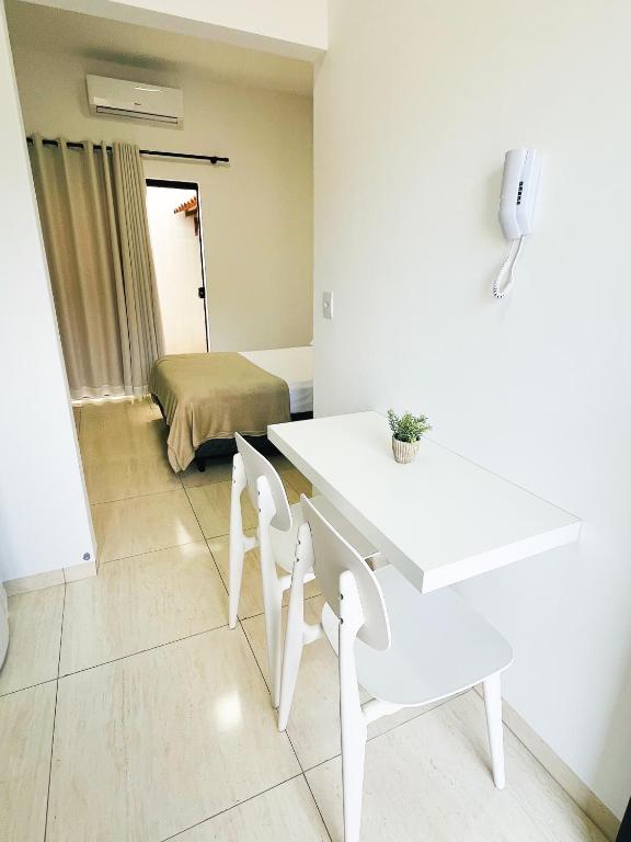 a white table and chairs in a room with a bed at Ap3 - Studio Confortável e Tranquilo in Guaíra