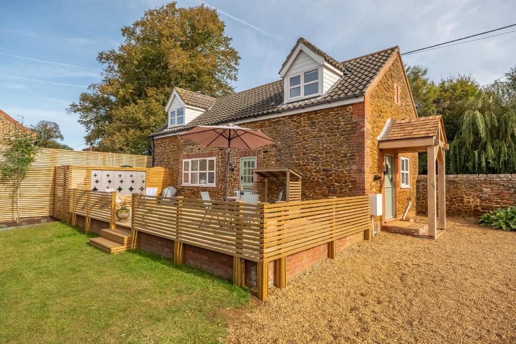 a house with a deck with an umbrella at No33 WOODLANDS BOUTIQUE COTTAGE in Heacham